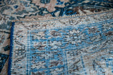 Underside detail of a distressed Heriz rug, showing hand-knotted blue selvedge and ivory weave.