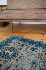 Distressed vintage Persian Heriz rug detail with meandering blue patterns on antique ivory.