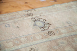 Textured sandy beige Oushak rug pile, featuring a dark brown stylized floral pattern.
