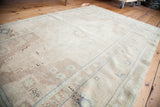Hand-knotted pile of a vintage Oushak rug with sandy beige and muted traditional motifs.