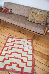 Stepped geometric pattern of a vintage 1960s Tulu rug in coral red and off-white.