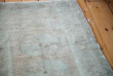 Edge detail of the vintage Oushak rug with sandy beige and sea foam green pile.