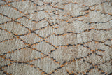 Close-up of shaggy Moroccan rug pile with ivory, apricot, and grey geometric pattern.