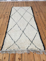 Shaggy ivory pile, sharp black lattice diamond pattern, and light fringe on the Moroccan runner.