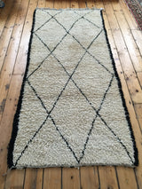 Shaggy pale ivory pile, black side edge, and simple fringe of the Moroccan runner.