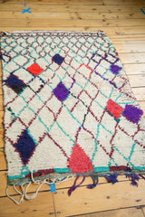 Vintage Moroccan rug's fringe with purple, blue, red tassels, and turquoise woven edge.