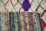 Close-up of vintage Moroccan rug pile, vibrant purple geometric accent, and colorful woven foundation.