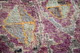 Textured pile close-up of vintage Moroccan rug with eggplant purple, grey, and gold medallion motif.
