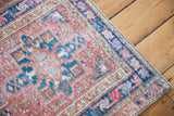 Vintage Persian Karaja rug corner featuring geometric red, teal, and ivory patterns.