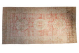 Distressed antique Khotan carpet with a triple medallion design in red, ivory, and beige.