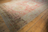 Long angle view of an antique Khotan carpet's distressed red field and neutral-toned medallions.