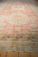 A long perspective view of an antique Khotan carpet's triple medallions and soft red field.