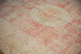 Distressed texture of an antique Khotan carpet's medallion in soft red and pale ivory.