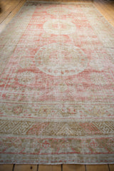 Angled view down the length of the distressed antique Khotan rug, showing its triple medallions.