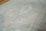 Geometric medallion and border details of a vintage Oushak rug in peach, grey, and ivory.