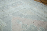 Muted peach, grey, and ivory geometric pattern on vintage Oushak rug pile.