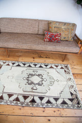 Angled view of vintage Oushak rug, displaying minimalist geometric pattern in sea foam green and ivory.