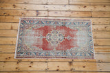 Distressed Oushak rug's central medallion and border, featuring soft red and sky blue patterns.