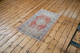 Distressed Oushak rug showing its allover wear, soft red field, and sky blue accents.