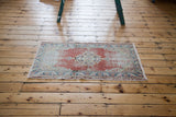 Distressed Oushak rug's soft red field displays allover wear with faded blue motifs.