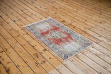 Textured corner of distressed vintage Oushak rug, showing soft red and sky blue details.