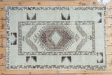 Distressed vintage Turkish Oushak rug, striking ivory and charcoal geometric medallion.