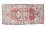 Distressed Oushak rug with pale ivory medallion, charcoal serrated leaf motif, on faded red.