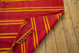 Vintage Moroccan Kilim corner showing reversible orange and yellow stripes, colorful tassels.