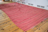 Frayed end of the vintage Moroccan Kilim runner, with soft cranberry red flatweave stripes.