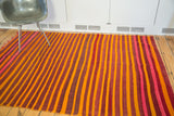 Vibrant eggplant, fire orange, and pink stripes on a flat-woven wool kilim.