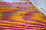 Textured hand-woven vintage Moroccan kilim showing eggplant, bright pink, and fire orange stripes.
