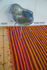 Vintage Moroccan kilim with textured eggplant, bright pink, and fire orange stripes.