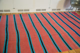 Geometric stripe pattern on a vintage Moroccan kilim with pink, blue, and black.