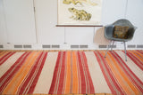 Soft wool flatweave texture of vibrant cranberry, orange, ivory, and grey stripes.