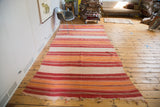 Vintage Moroccan Kilim runner featuring vibrant red, orange, and ivory stripes with fringed end.