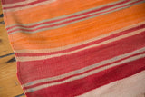 Close-up of the vintage Moroccan Kilim's soft wool, with orange, cranberry red, ivory, and grey stripes.