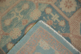Folded corner of Khotan rug reveals low aqua pile and geometric aqua, peach-red backing.