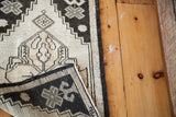 Folded detail of the Oushak rug, showing contrasting black and ivory geometric patterns.