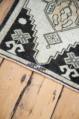 Vintage Oushak rug's angled corner detail showing black and ivory geometric pattern and fringe.