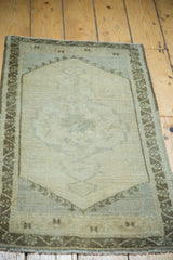 Muted earth tones and soft texture of the vintage Oushak rug mat's central medallion.