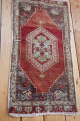 Textural wear on the vintage distressed red Anatolian runner's corner and fringe.