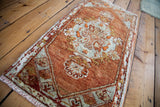 Vintage Oushak rug detail with tomato orange, grey, and ivory floral motifs.