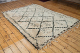Textured ivory pile, charcoal black harlequin motif, and fringe on vintage Moroccan rug.