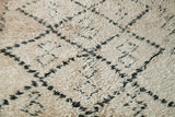 Fluffy ivory pile close-up on a Moroccan carpet with charcoal diamond and harlequin motifs.