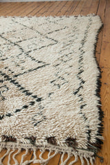 Vintage Moroccan rug with textured pile, showing ivory, charcoal, and brown harlequin motifs and fringe.