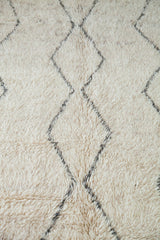 Textured view of vintage Beni Ourain rug showing shaggy ivory pile and grey diamond motif.