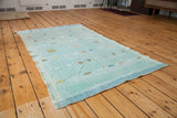 Angled view of the vintage kilim rug showcasing its light blue ground and scattered geometric motifs.