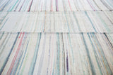 Hand-woven rag rug texture with subtle stripes of ivory, pastels, and charcoal.