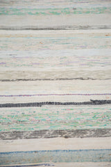 Hand-woven texture of a vintage rag rug featuring striped pastels and neutral linen.