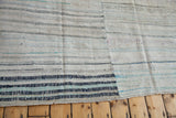 Corner of vintage rag rug, hand-woven ivory, charcoal, navy, and light blue striped pattern.